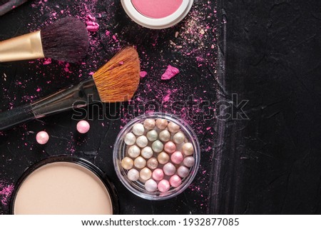 Make up brushes, pearls, and powder, shot from above on a dark background with copyspace