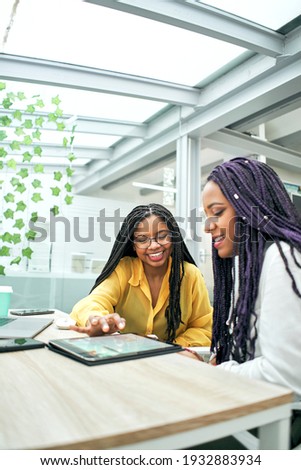 Happy businesswoman colleagues in modern office using tablet. Royalty-Free Stock Photo #1932883934
