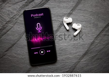 Wireless earbuds and mobile phone with podcast app on the screen