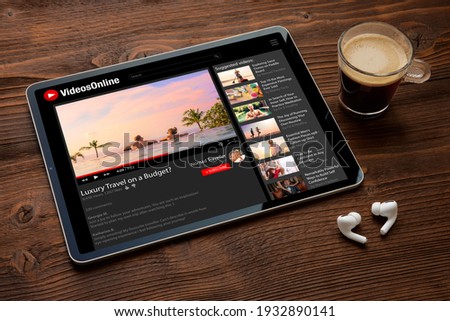 Online video website on the screen of digital tablet with wireless earphones next to it