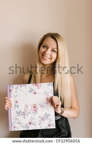 The girl holds in her hands beautiful photo albums or photo books in the spring style