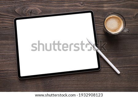 Tablet mockup with blank white screen and wireless stylus pen on dark wooden table