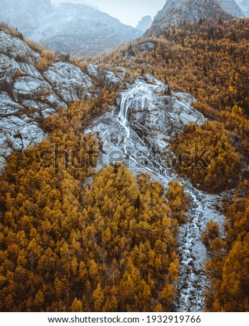 Aerial view of autumn mountain waterfall. Mountain forest waterfall in golden autumn.