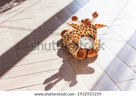 Children's soft plush toy giraffe sit on wooden background, hard light and shadow