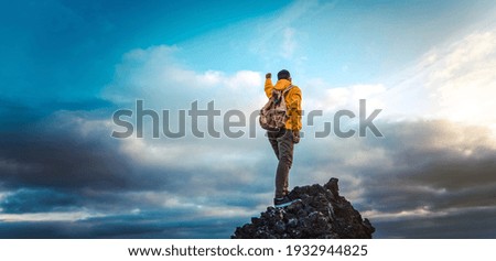 Hiker with backpack raising arms up on the top of the mountain - Successful man celebrating victory  Royalty-Free Stock Photo #1932944825