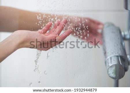 Woman taking a shower at home - female hands tryimg the temperature of water in shower Royalty-Free Stock Photo #1932944879