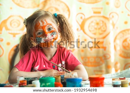 Child girl drawing paint with paint of face. Art-therapy.