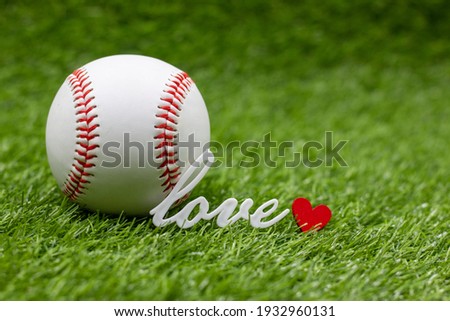 Baseball with love word and red heart for Valentine's Day or Wedding are on green grass background