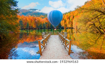 Hot air balloon flying over autumn forest landscape reflection on the water with wooden pier - Autumn landscape in (seven lakes) Yedigoller Park Bolu, Turkey