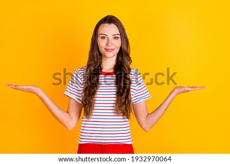 Portrait of attractive content cheerful girl holding on two palms copy space offer idea isolated over bright yellow color background