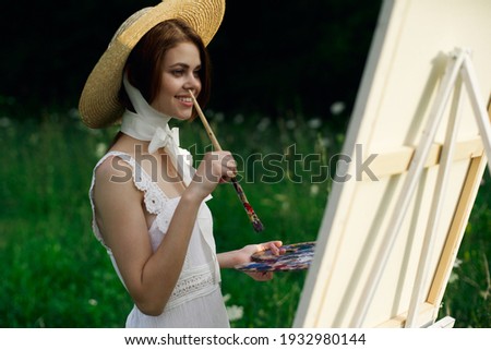 woman artist in hat outdoors near canvas art hobby