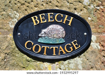 Stone Wall and Cast Metal Oval Sign with Hedgehog and Name 'Beech Cottage' 