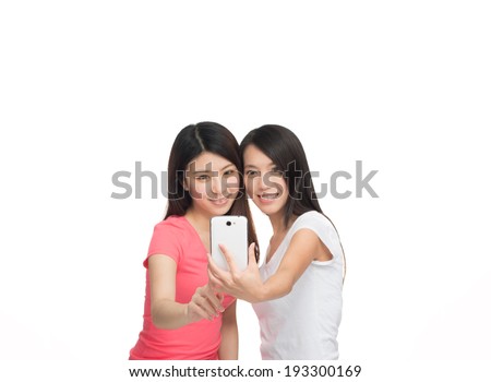 Two beautiful asian girls making a selfie, focus on the mobile phone.
