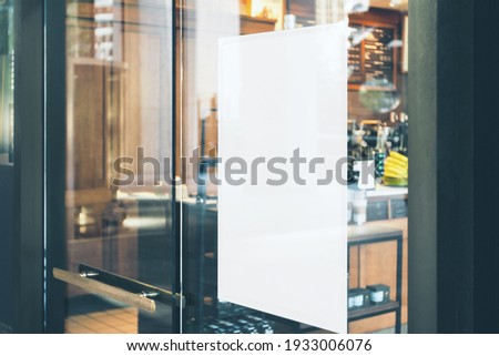 Blank white sign on glass door before cafe entrance. Mockup