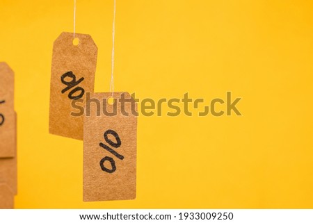 Tags with drawn percentages hang on strings on a yellow background, concept of discounts and sales