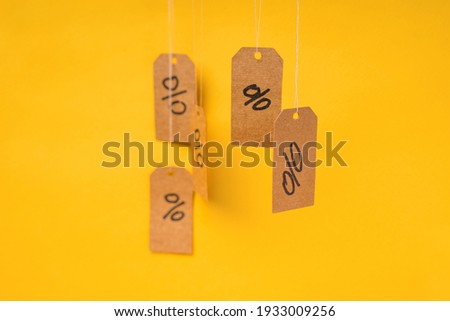 Tags with drawn percentages hang on strings on a yellow background, concept of discounts and sales