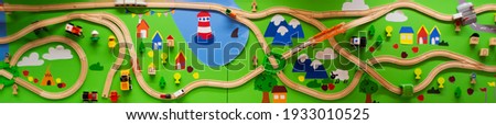 Banner with wooden children's railway with a bridge, roundabout, road signs, houses, trees and white trains and cars on a green background