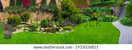 Garden stone path with grass growing up between the stones.Detail of a botanical garden. Royalty-Free Stock Photo #1933026821