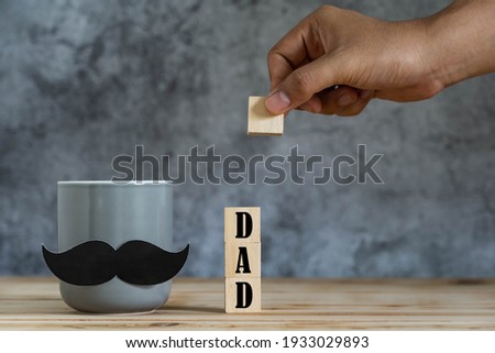 Objects on the table of  Happy Fathers day holiday background concept.Coffee mug with mustache and  DAD text on cube wood block.sign for celebration of festival daddy.mock up, border,banner,