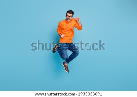 Full length photo of delighted person jump high fists unbelievable achievement isolated on blue color background