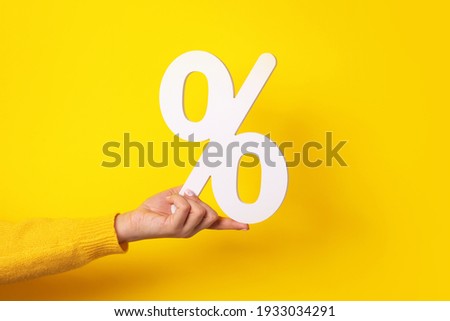 hand holding percentage sign over yellow background Royalty-Free Stock Photo #1933034291
