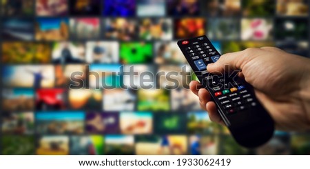 tv channels in background and remote control in hand. smart television and content on demand concept