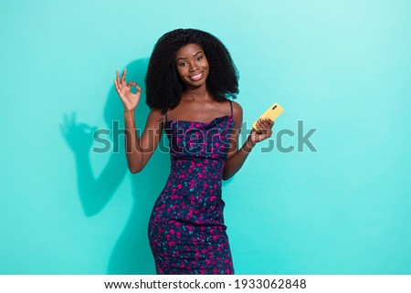Photo portrait woman smiling keeping mobile phone showing okay gesture happy isolated vibrant turquoise color background