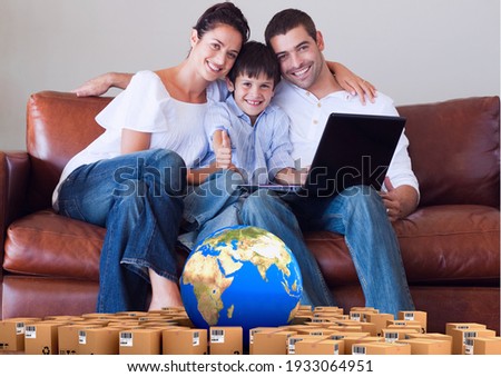Composition of cardboard boxes with globe and couple with son using laptop at home. moving house, global shipment and delivery concept digitally generated image.