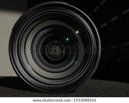 Camera lens with lens reflections in the male hand of a young man. Dark background. Bracelet on the arm. Colored highlights and reflections. Macro. Glass and reflection.