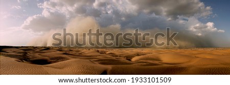 An image showing a severe sandstorm of high altitude with cumulonimbus rain clouds forming near towering mountains heading towards a sandy desert. 