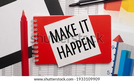 On the desktop are reports, charts, a red pen, a black marker, a red notepad and a white sheet of paper with the text MAKE IT HAPPEN. Business concept