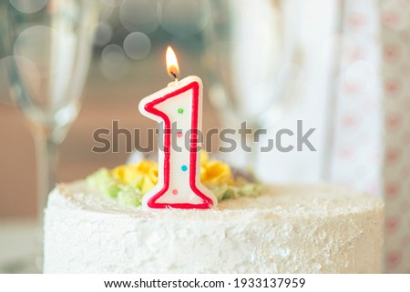 Birthday candle as number one  on top of sweet cake on the table, concept picture