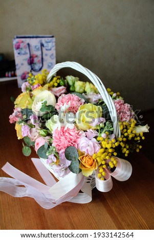 Festive basket with different flowers on a wooden table