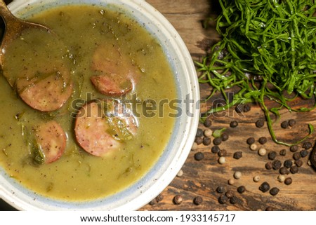 delicious green broth with pepperoni and cabbage top view with golden spoon on rustic wooden table with selective focus