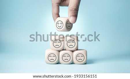 world mental health day concept or feedback rating and positive customer review, Businessman hand choose and turn sad face to smile face, wood cube stacking with sadness face icon on blue background Royalty-Free Stock Photo #1933156151