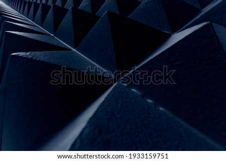 Dark blue abstract geometric pattern background. Pyramids relief with triangles shapes and lines. Volumetric polygonal detail of the soundproof wall. Infinite lines, modern and go forward concept. 