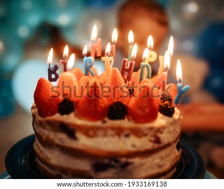 birthday cake with candles against blue balloons