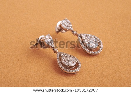 earrings with precious stones on color background