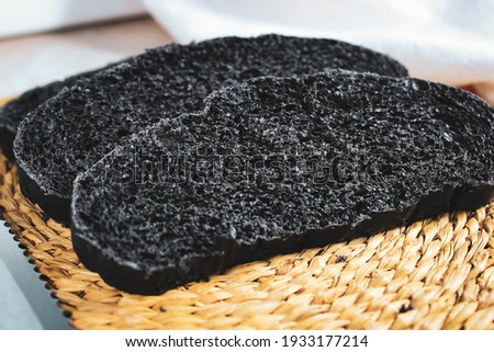 Pieces of black fresh bread with the addition of activated carbon on the table. Close-up, selective shot.