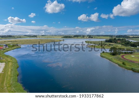 Aerial view with the pedestrian bridge over the lake Wangermeer in Hohenkirchen. Hohenkirchen belongs to the municipality of Wangerland and is located in the region East Frisia in Germany. Royalty-Free Stock Photo #1933177862