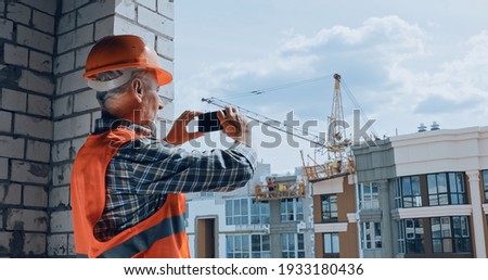 Builder taking photo with smartphone on construction site