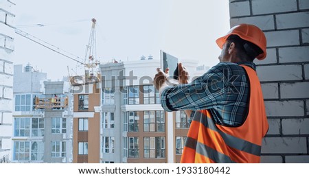 Builder taking photo with digital tablet on construction site