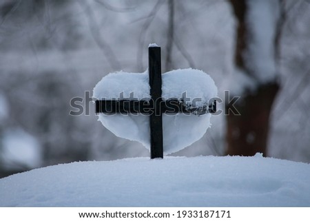 Heart-shaped Snow on a Cross.
A lot of snow covered everything on the  ground like the cemetery's gate and tombs. Here's a cross on the gate where a a heart-shaped snow covered it.