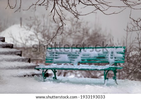 Winter Scene. Green Bench near the Stairs in the Park Covered with Snow. Wintertime Outdoors.