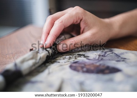 Eco print process: Female hands unrolling a bundle of fabric or 