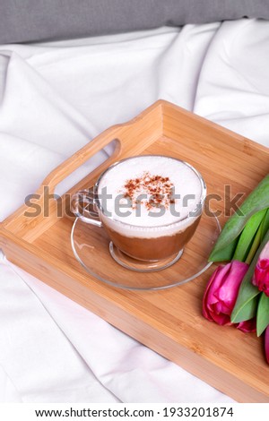 Coffee with cinnamon and pink tulips on the wooden tray in bed. Romantic surprise