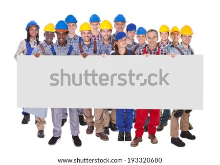 Portrait of multiethnic manual workers holding blank banner against white background