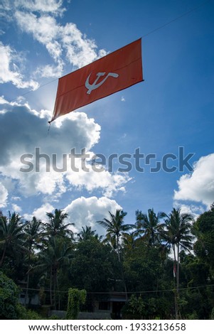  communist flag. Hammer and sickle representing the peasants and the workers, flying in the thick cloudy blue sky.