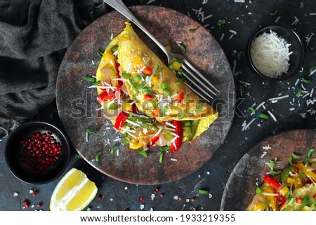 Healthy breakfast food: stuffed omelette with vegetables on dark background. Top view with copy space.