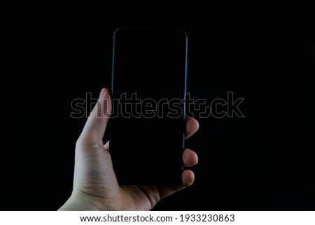 Phone in hand on a black background.